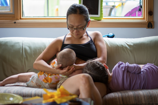 Mother breastfeeding baby comforting child on couch