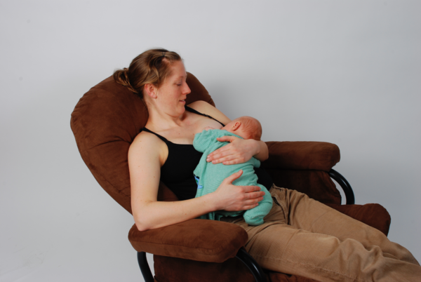 Mother breastfeeding baby in a chair