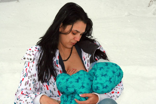 Mother breastfeeding baby in cold weather
