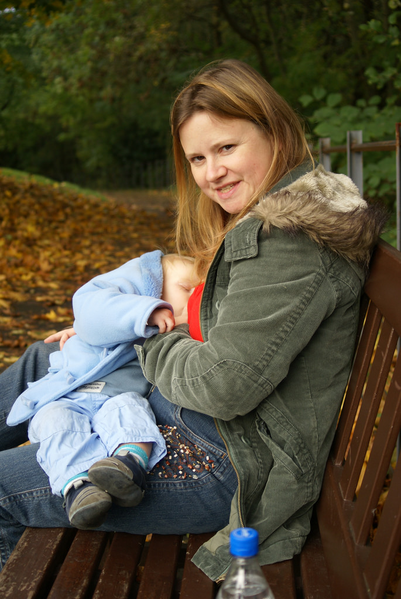 Mother breastfeeding baby on a park bench